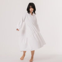 白いワンピースの裾を遊ばせるポージングの女性の写真