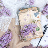 紫のライラックを散らした白紙の便箋と紐で縛った手紙の写真