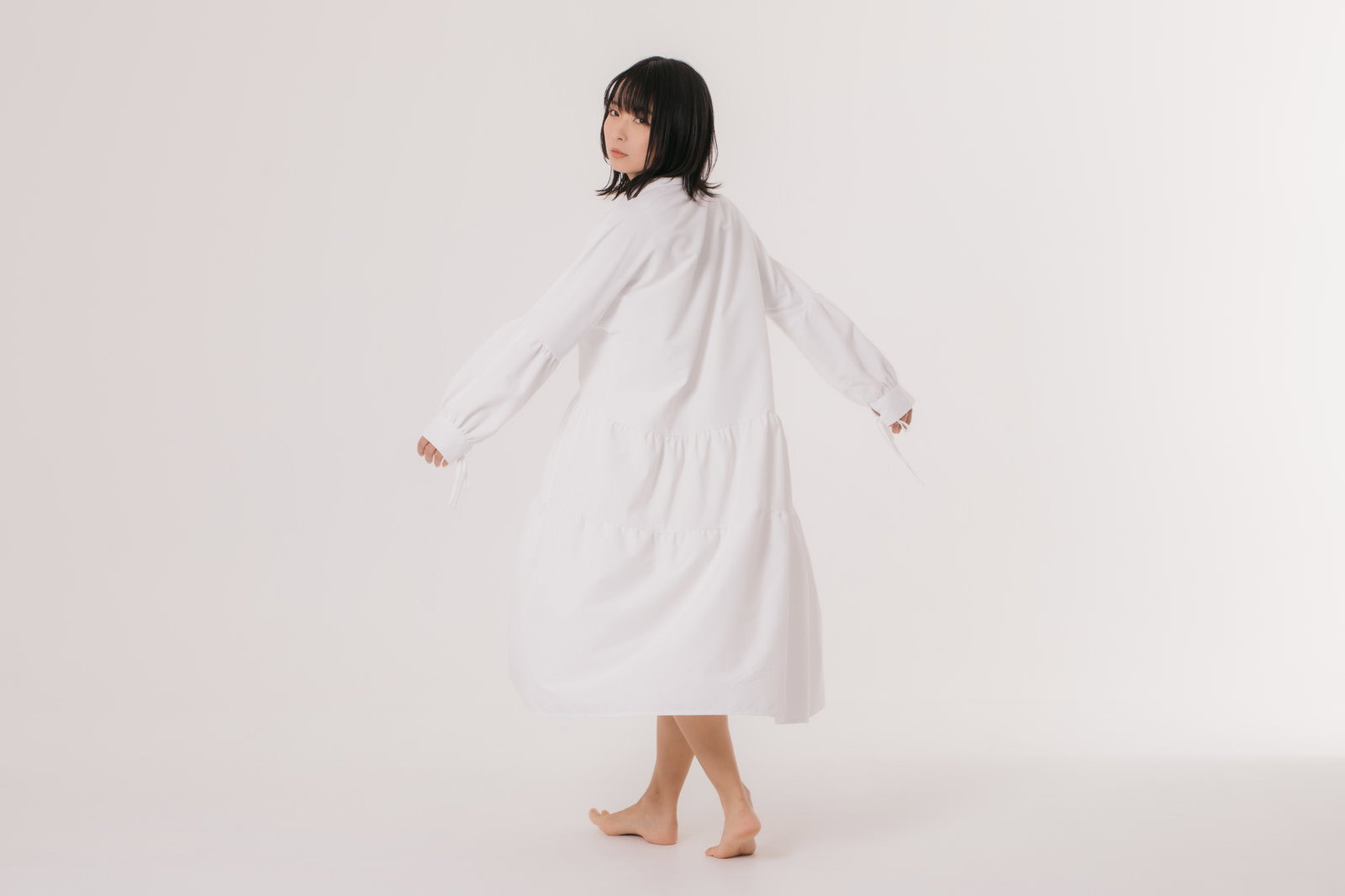 白いワンピースを着て振り向くポーズをとる女性［モデル：にゃるる］