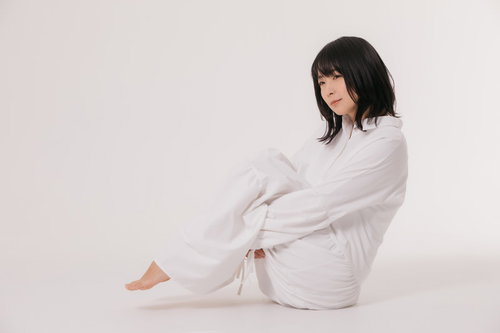 白いワンピースで小山座りするリラックスポーズの女性