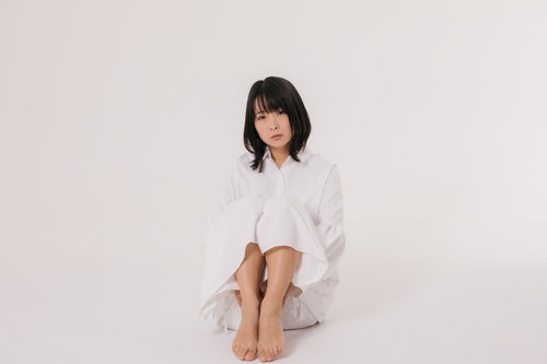 白いワンピースで太腿を抱えて座る女性のポートレート