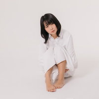 男性用のYシャツを着用してリラックスして座る女性の写真