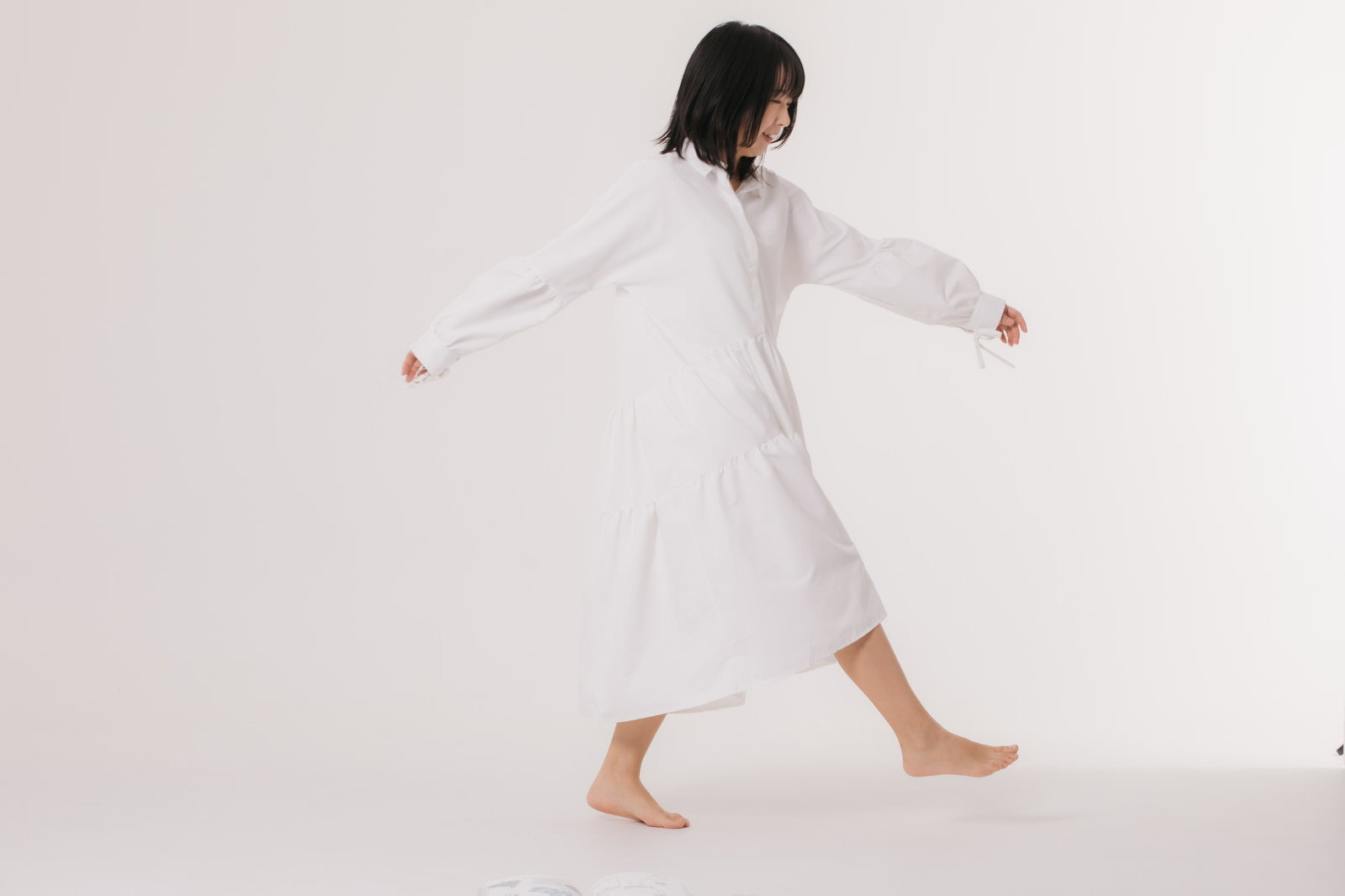 白いワンピースを着た女性が両腕を広げて歩いている後ろ姿［モデル：にゃるる］