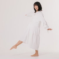 白いワンピースで片足を上げてバランスをとる女性モデルの写真