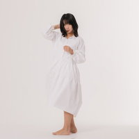 髪を押さえて振り返る白いワンピース姿の女性モデルの写真