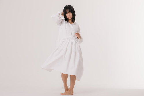 白いワンピースを試着して髪を押さえながら振り返る女性