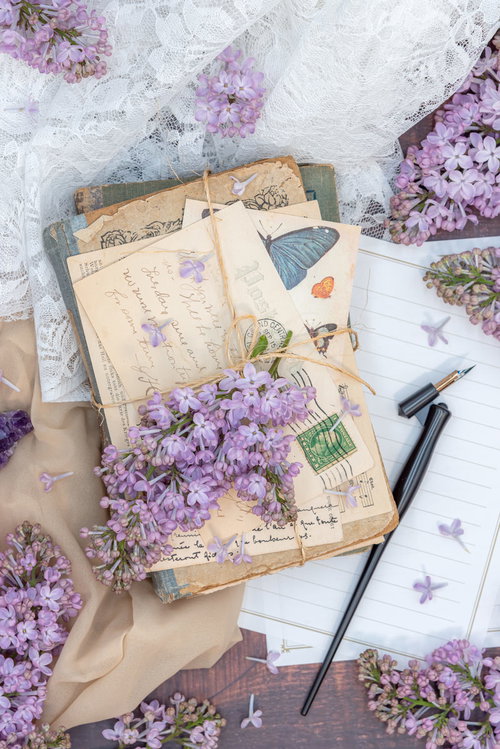 纏めた手紙と便箋の上に置かれたライラックの生花