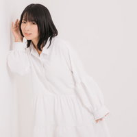 隣人の話し声が聞こえないか壁に耳を当てて確認する女性の写真