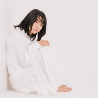 白い服を着て膝を抱えて丸くなって座り込む女性の写真