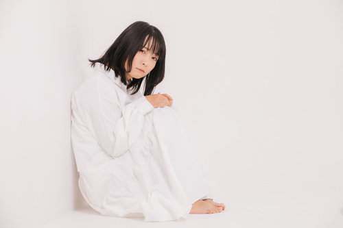 白い服を着て膝を抱えて丸くなって座り込む女性