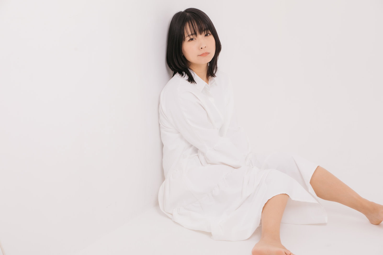 白いトップスを着た女性が壁際に座り込んでいるポーズ［モデル：にゃるる］