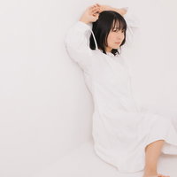 壁に寄り掛かってポージングする長髪の女性モデルの写真