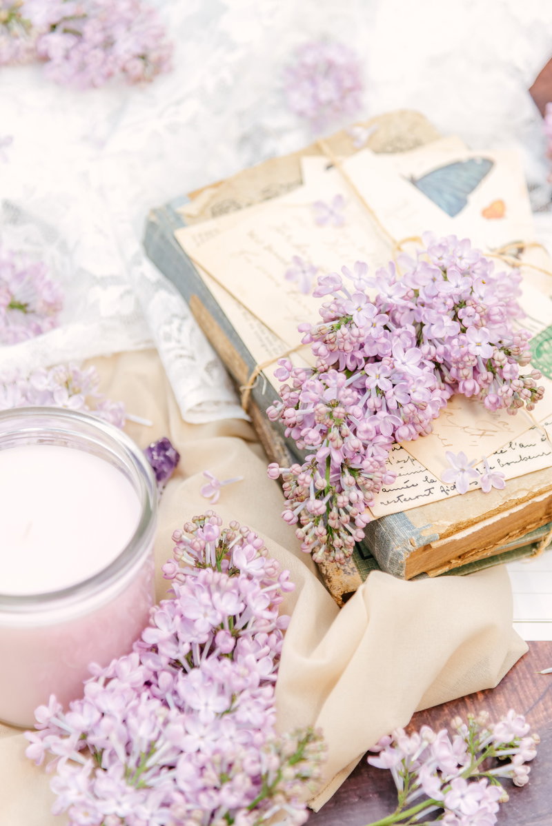 開かれた古本の上に淡い紫色のライラックの花が散りばめられている様子