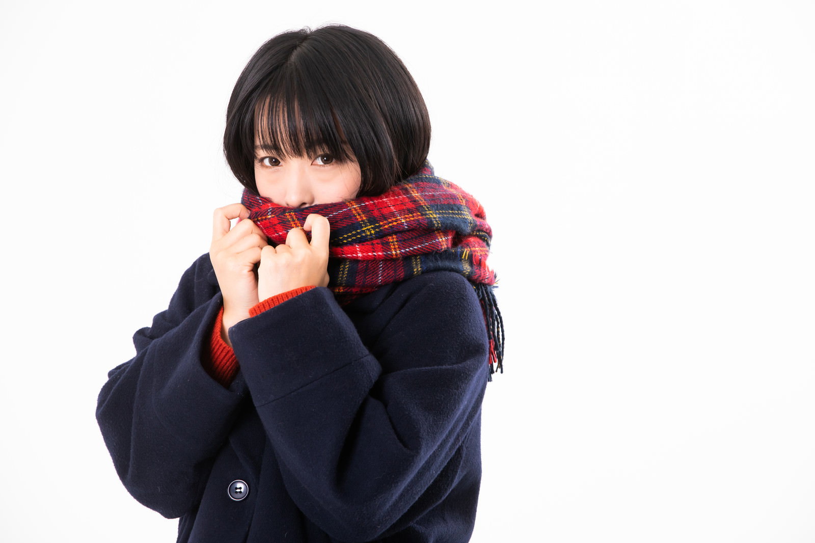 赤いチェックのマフラーを両手でギュッと握る女性［モデル：にゃるる］