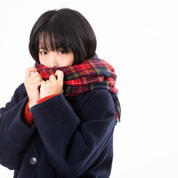 赤いチェックのマフラーをギュッと握る冬の女性の写真