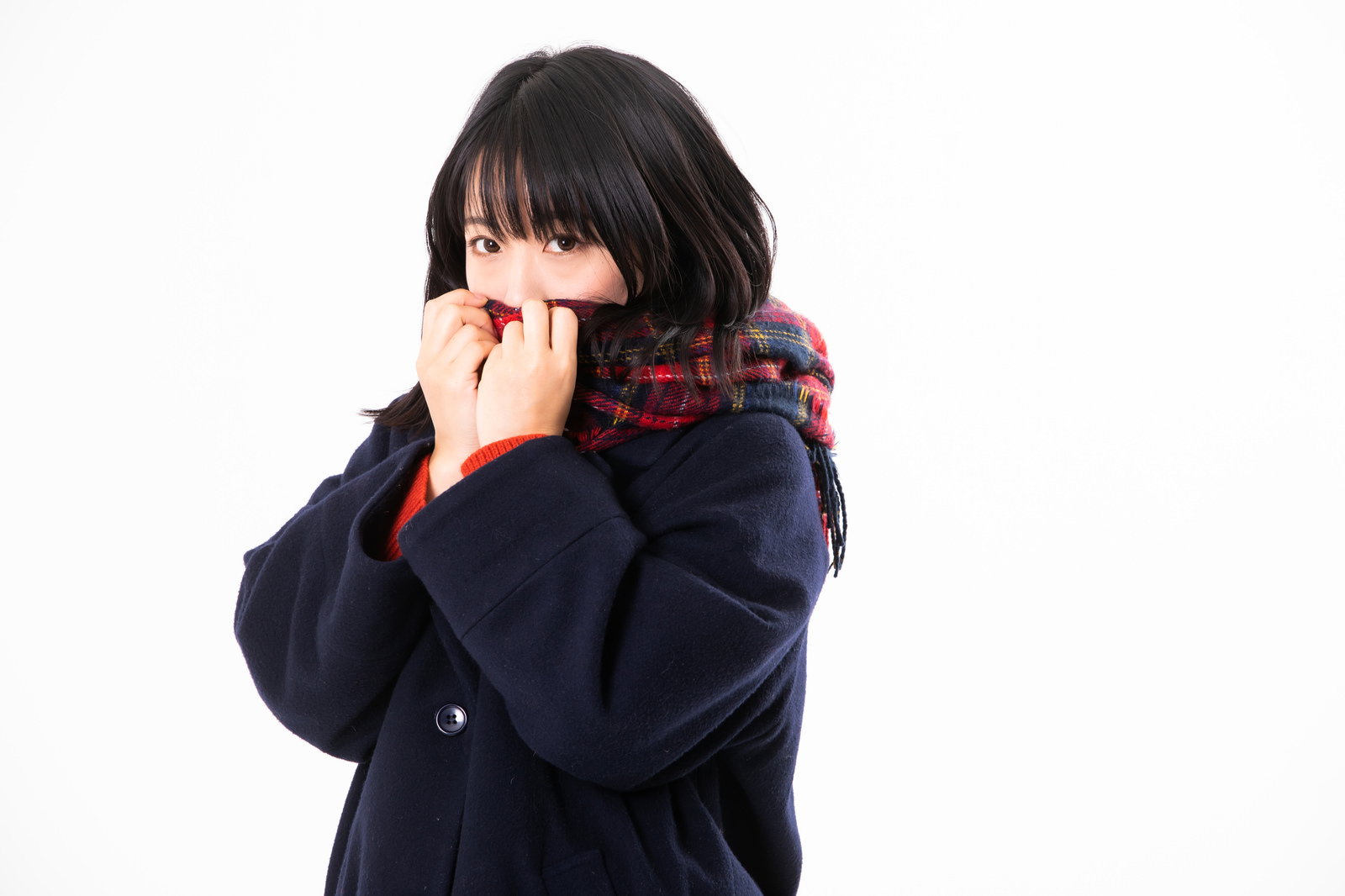 紺色のマフラーで口元を隠し、寒そうにしている女性［モデル：にゃるる］
