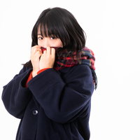 紺色のマフラーで口元を隠す厚着した寒がりな女性の写真