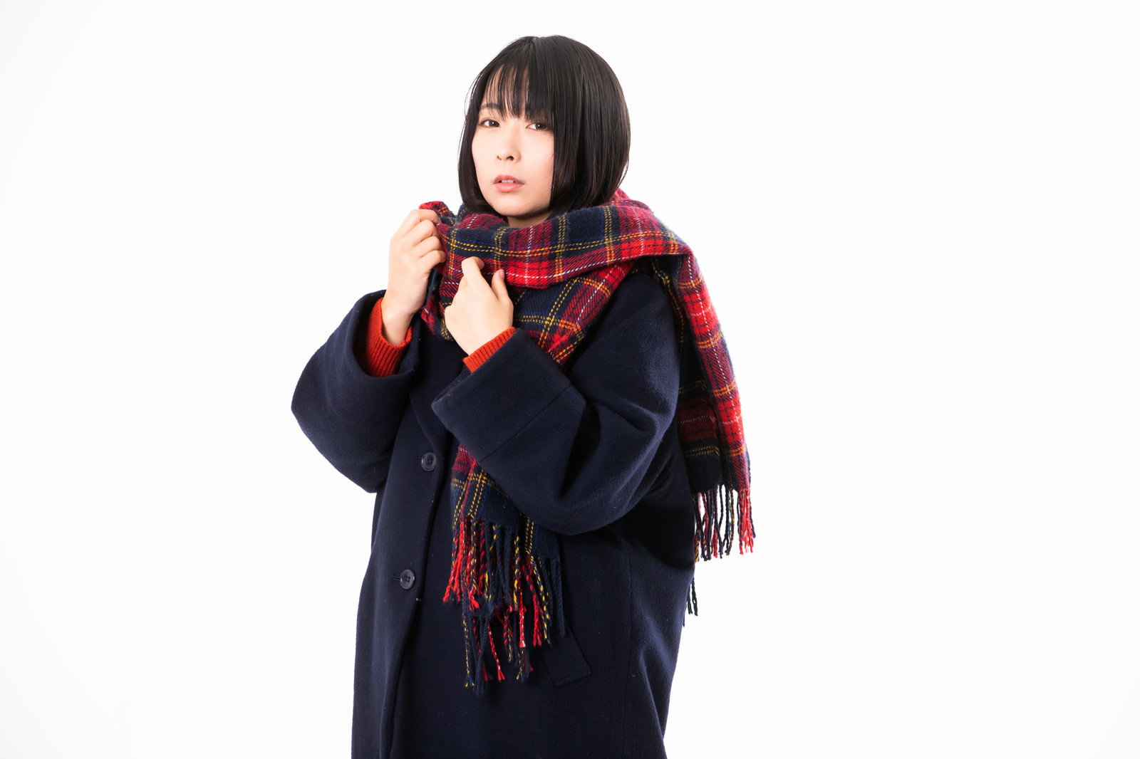 赤いチェック柄のマフラーを首に巻き紺色のコートを着た女性［モデル：にゃるる］