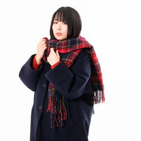 赤いチェック柄のマフラーを首元に巻く女性の写真