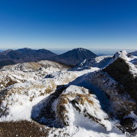 日光白根山山頂から見る雪に覆われた男体山の写真
