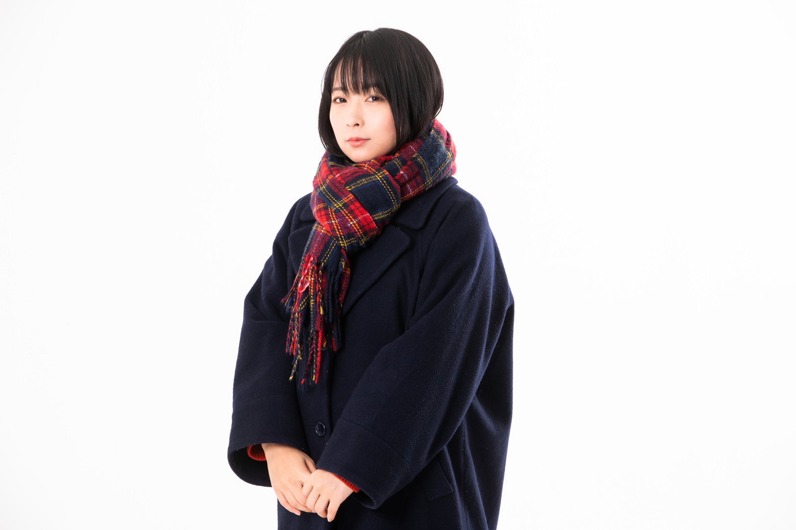 赤いチェック柄のマフラーを巻き黒いコートを着た女性［モデル：にゃるる］