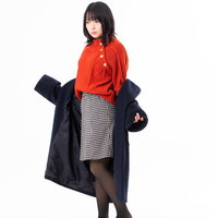 コートを脱ぎかける女性のポーズ|季節の変わり目の衣替えの写真