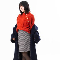 室内で紺色のコートを脱ぐ女性のポーズの写真