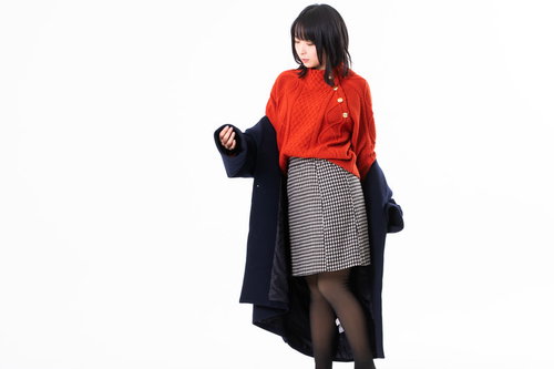 黒いコートを脱ぐ赤いニットの女性のポーズ