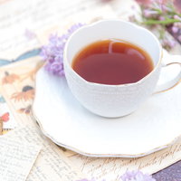 ライラックを添えた白いティーカップの紅茶の写真