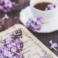 古い洋書に添えた紫色のライラックと珈琲のある読書風景の写真