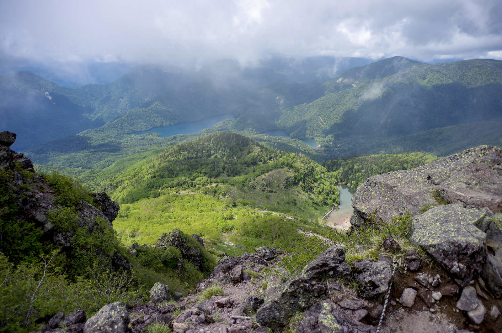 日光白根山山頂の岩場から見下ろす緑の山々と雲海の景色