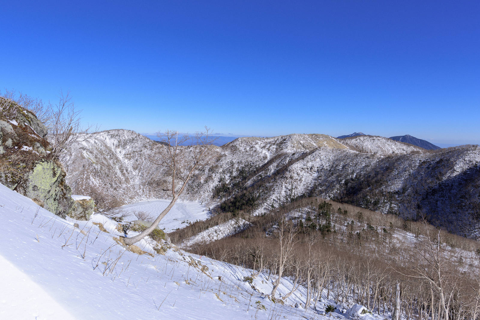日光白根山山頂稜線から望む雪に覆われた五色沼方面の冬山景色