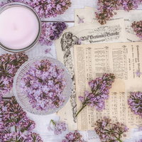 散らばるライラックの花と楽譜とキャンドルのテーブルスタイリングの写真