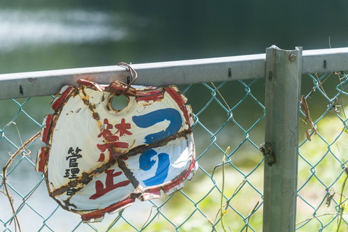 釣り禁止の警告が書かれた劣化した金属フェンス取付け看板