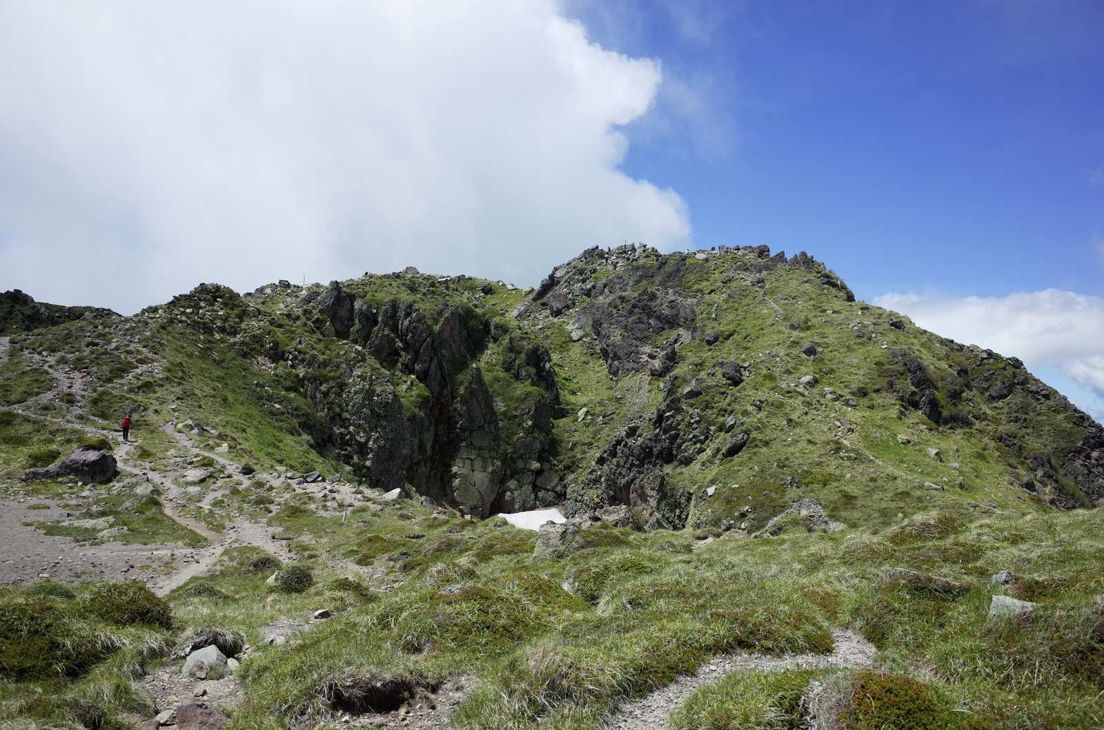 青空の下に広がる日光白根山の山頂周辺、緑の山肌と岩場