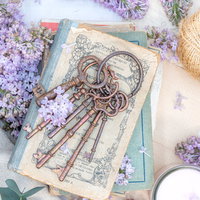 古書の上に無造作に置かれた鍵とライラックの花の写真