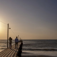 千葉県南房総市・原岡桟橋で夕日を背景にするデート中のカップルの写真
