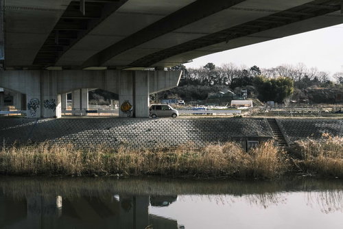 冬枯れの川沿いに立つ高架橋と橋桁