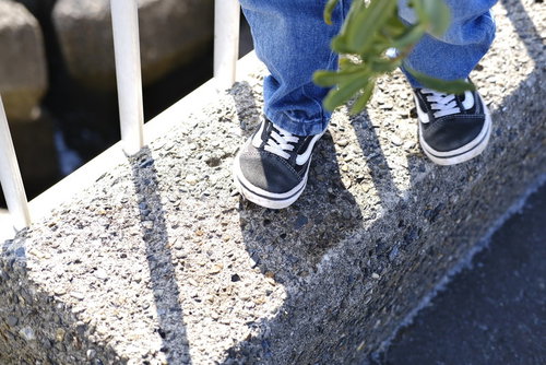 散歩中の子供が白と紺色のスニーカーで歩く足