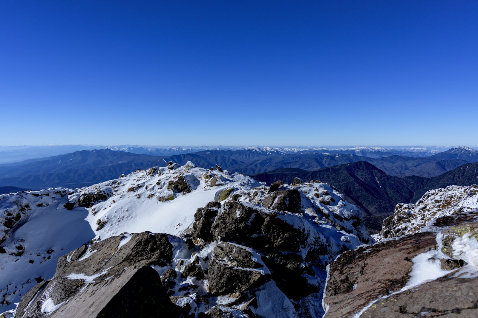 雪に覆われた日光白根山の山頂から西側方面の雪山を望む青空の風景