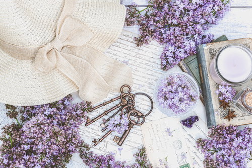 白いレースに麦わら帽子、アンティークな鍵とライラックの花を配置したフラットレイ