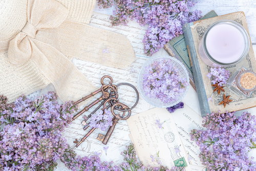 白いテーブルに紫のライラックと鍵、洋書、帽子を配置した雑貨