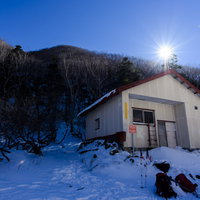 積雪期の日光白根山避難小屋と月夜の冬山風景の写真
