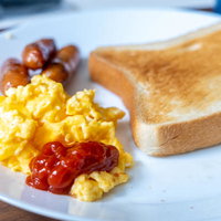 朝食のスクランブルエッグとトーストにケチャップの写真