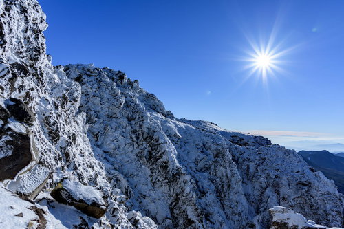 陽光照り付ける日光白根山の氷の岸壁と光芒