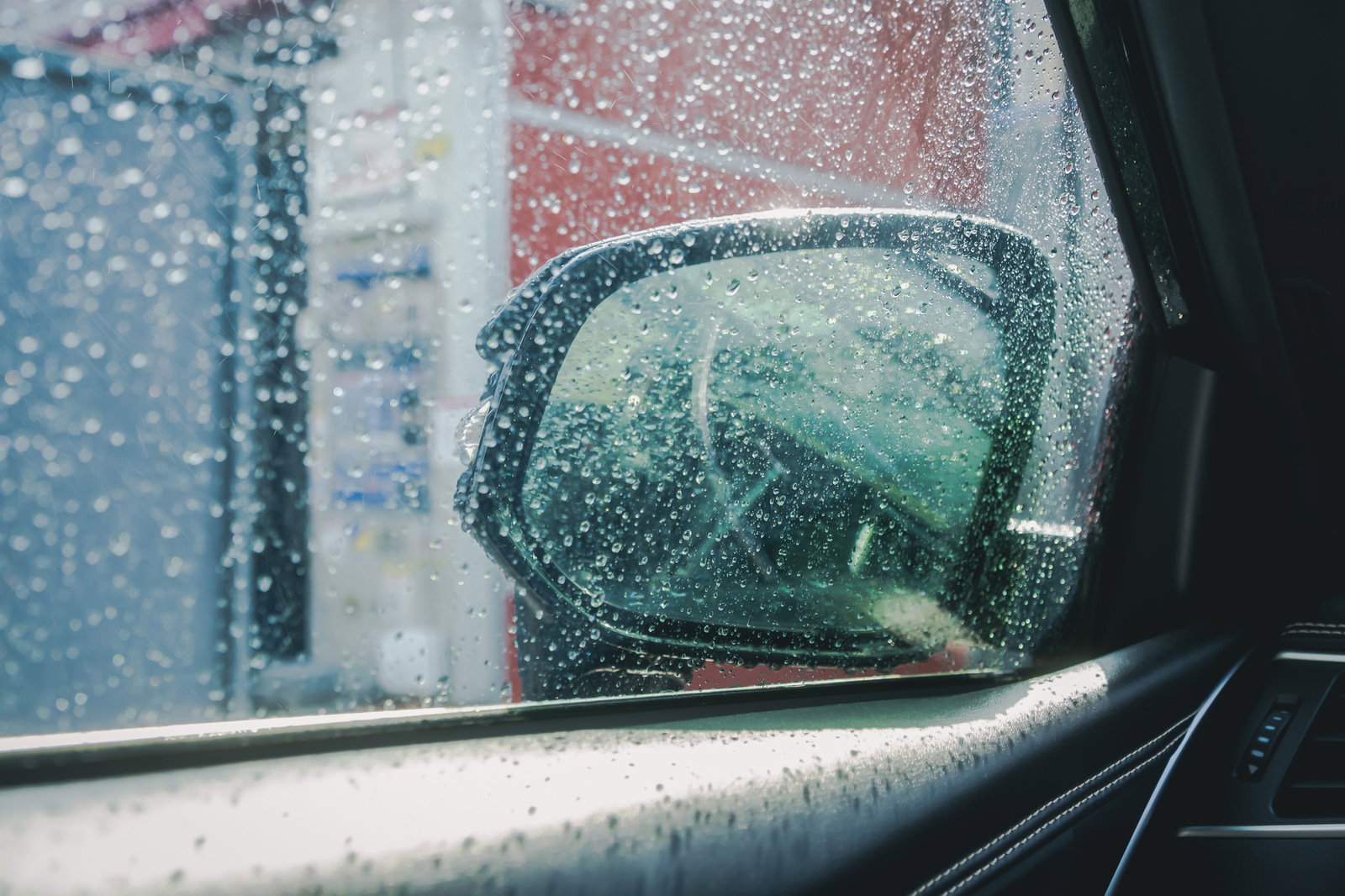 雨で濡れた車のサイドミラーとサイドガラスに水滴が付着している様子