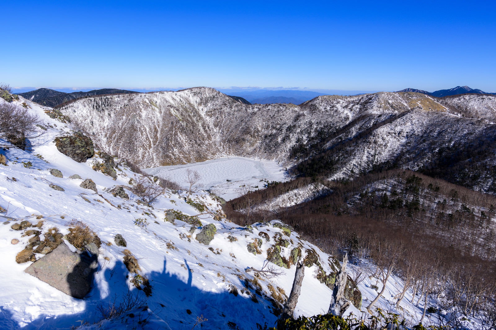 日光白根山の山頂付近から見下ろす雪に覆われた外輪山と谷底の雪原