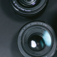 机の上に並べられたカメラレンズと一眼レフの撮影機材の写真