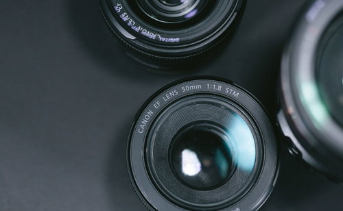 机の上に並べられたカメラレンズと一眼レフの撮影機材