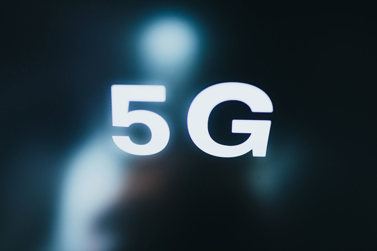 暗い背景に白い5Gの文字と青い光が輝く